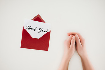cropped shot of woman holding hands near opened red envelope with thank you lettering on paper isolated on white