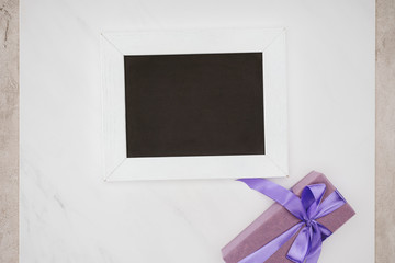 top view of blank chalkboard with gift box on white