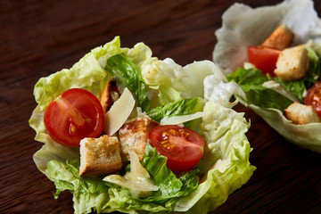 Yummy top view composition of fresh healthy salad served in lettuce leaves on wooden table.