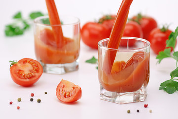 Tomato juice pouring into a glass on white.