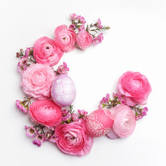 Easter eggs and ranunculus flowers frame on white background. Flat lay