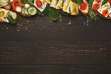 Variety of healthy vegetarian sandwiches on dark wood, top view