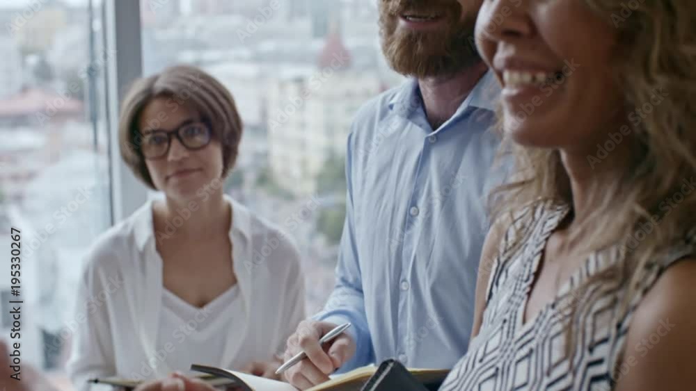 Poster group of colleagues standing by large window in office, smiling and showing agreement with suggestio