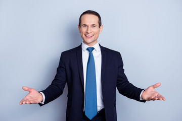 Cheerful, nice man in formal wear with tie having his hands open like hospitable gesture, you are welcome, well met, standing over gray background - obrazy, fototapety, plakaty