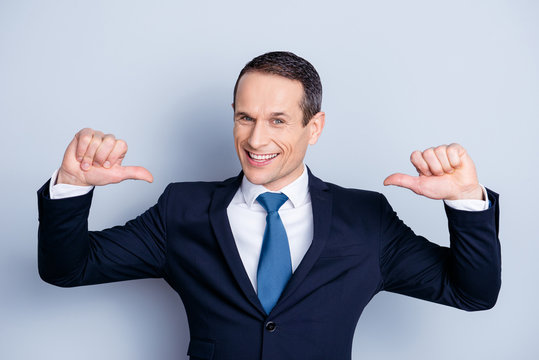 Cheerful financier, positive economist, confident politic man in formalwear with tie showing with two thumbs on himself,  standing over gray background