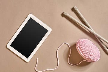 Plakat Pink knitting yarn ball, knitting needles and a tablet with a black screen, top view