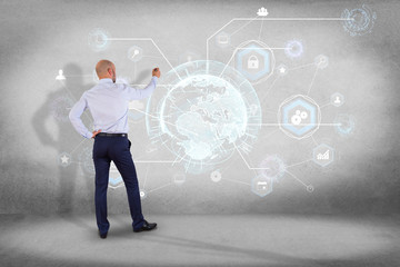 Businessman in front of a wall with an International business network connection displayed on a futuristic interface with technology icon and sphere globe - Worldwide business concept