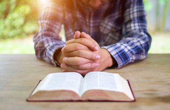 The man hands praying with a bible