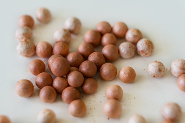 Close-up of brush and face makeup pearls in gentle pink shades on a white background. Shallow depth of focus. Concept of beauty fashion.