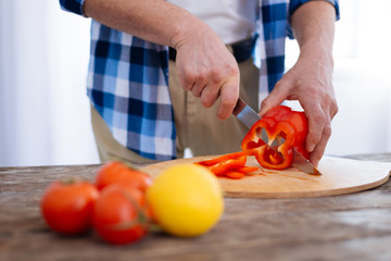 Vitamins source. Selective focus of male hands holding red bell pepper rifled with steel knife