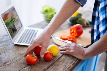 Nutrition biohacks. Selective focus of young strong male hands taking tomato for involving in biohacking diet and preparing dinner