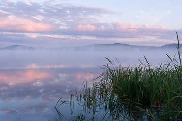 Fog over the river and pink clouds before summer dawn.