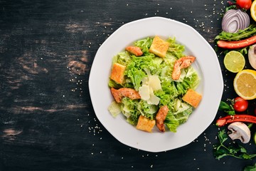 Caesar salad with chicken and fresh vegetables. On a wooden background. Top view. Copy space.