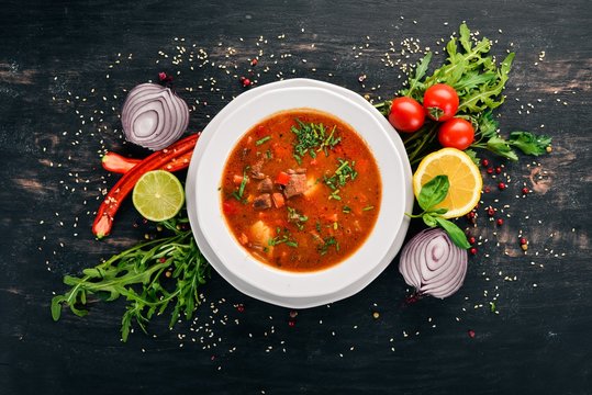 Soup with beef tomatoes and fresh vegetables. On a wooden background. Top view. Copy space.