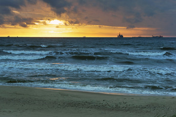 Sunset over the sea. Reflection of sunlight in the sea waves. Red sky in the rays of the sunset.