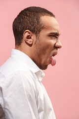 Young man with disgusted expression repulsing something, isolated on the pink