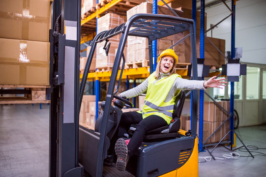 Woman warehouse worker with forklift.