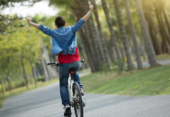 happy woman cyclist riding bike in spring tropical park