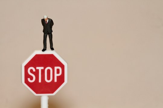 uomo d'affari in miniatura su un segnale di stop - concetto di licenziamento