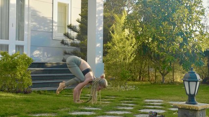 Professional performance of asana yoga by a young girl at backyard of her house