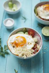 cous cous bowl with vegetables and fried egg on a turquoise wooden background