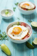 cous cous bowl with vegetables and fried egg on a turquoise wooden background