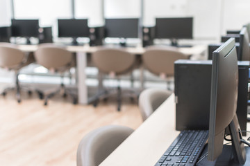 Computer lab blur background with pc desktop computer machine in blurry school class or office desk workspace