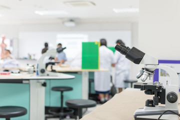 Biology or chemistry science class study with microscope and blur background of school student group learning in blurry lab classroom with teacher for education concept