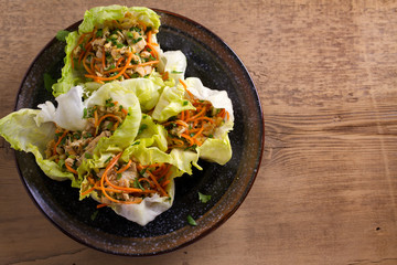 Lettuce wraps with chicken, carrot, peanuts and scallion. Stuffed iceberg lettuce leaves with chicken. View from above, top