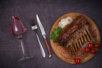 Grilled rack of lamb in balsamic vinegar and brown sugar sauce, glass and bottle of wine. Lamb chops with vegetables. Red wine and meat