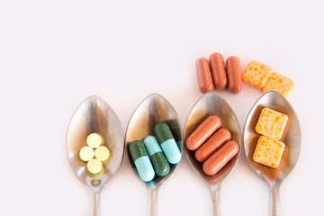 Drugs in spoon,Colorful of oral medications on White Background,drugs or pills health care concept