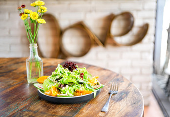 Smoke salmon dumpling salad on a white plate and on a light wooden table. Chinese food. Food chopsticks. In the frame, the hand holds the dumpling with chopsticks. Side view with copy space. 