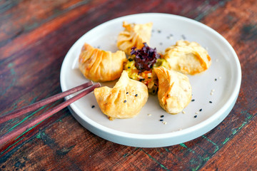 Dumping on a white plate and on a light wooden table. Chinese food. Food sticks. Side view with copy space. 