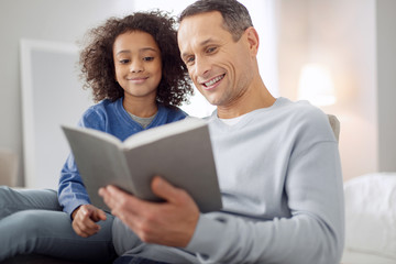 Favourite activity. Good-looking alert dark-haired reading a book and the girl sitting near him and smiling