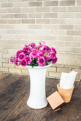 White vase with bouquet of beautiful chrysanthemums on brick wall background. vintage filter
