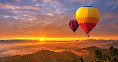Colorful hot-air balloons flying over misty morning sunrise at Chiang Mai, Thailand..