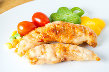 Grilled chicken breast with fresh vegetables on white plate