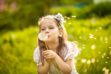Small girl blowing dandelion