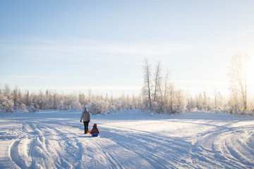 Mother and child sledding in winter 