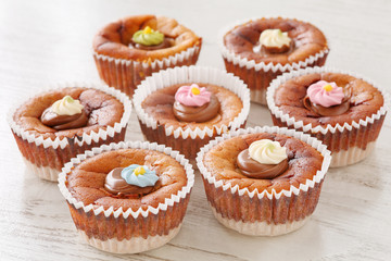 Seven delicious homemade mini cheesecakes with melted chocolate and colorful sugar sprinkles on a wooden table
