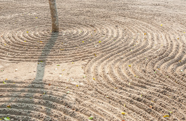 Fototapeta na wymiar Simple spiritual patterns in a Japanese Zen Garden with lines raked Sand, Karesansui.