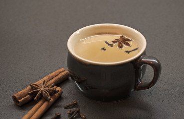 Indian tradition milk drink, masala chai tea with spices. Cinnamon Stick, Clove, Star Anise, Nutmeg and dark brown cup on stone background