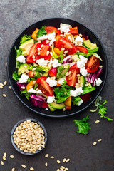 Vegetable dish, salad with avocado, pepper, tomato, italian mix, fresh lettuce, feta cheese and pine nuts. Healthy food. Top view
