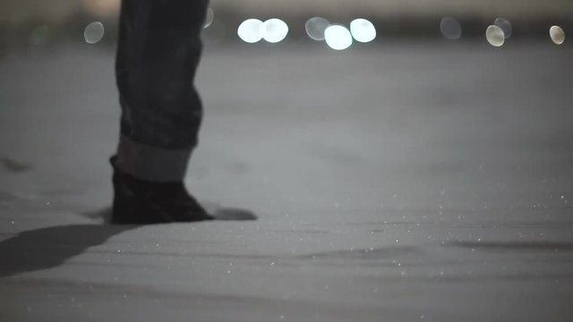 Close-up of woman's feet walking on the snow desert at night  . Stabiblized slow-motion shot moon light 