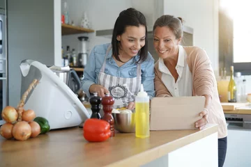 Crédence de cuisine en verre imprimé Cuisinier Amis cuisinant ensemble avec un robot de cuisine et une tablette