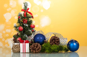 Little beautifully decorated Christmas tree, gifts, cones, toy-balloons, on yellow background