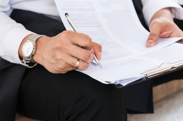 Unidentified young business man wearing white shirt use pen signing in contract to do policy agreement on documents