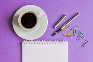 cup of black coffee with notebook,  and pen on ultraviolet background. business concept with copy space