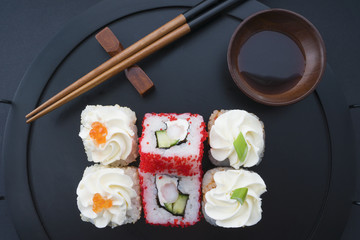 rolls on a black tray with chopsticks and soy sauce
