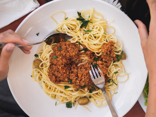 spaghetti bolognese in the plate. girl hands